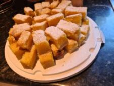 An image of a pile of lemon bars, coated in powder sugar.